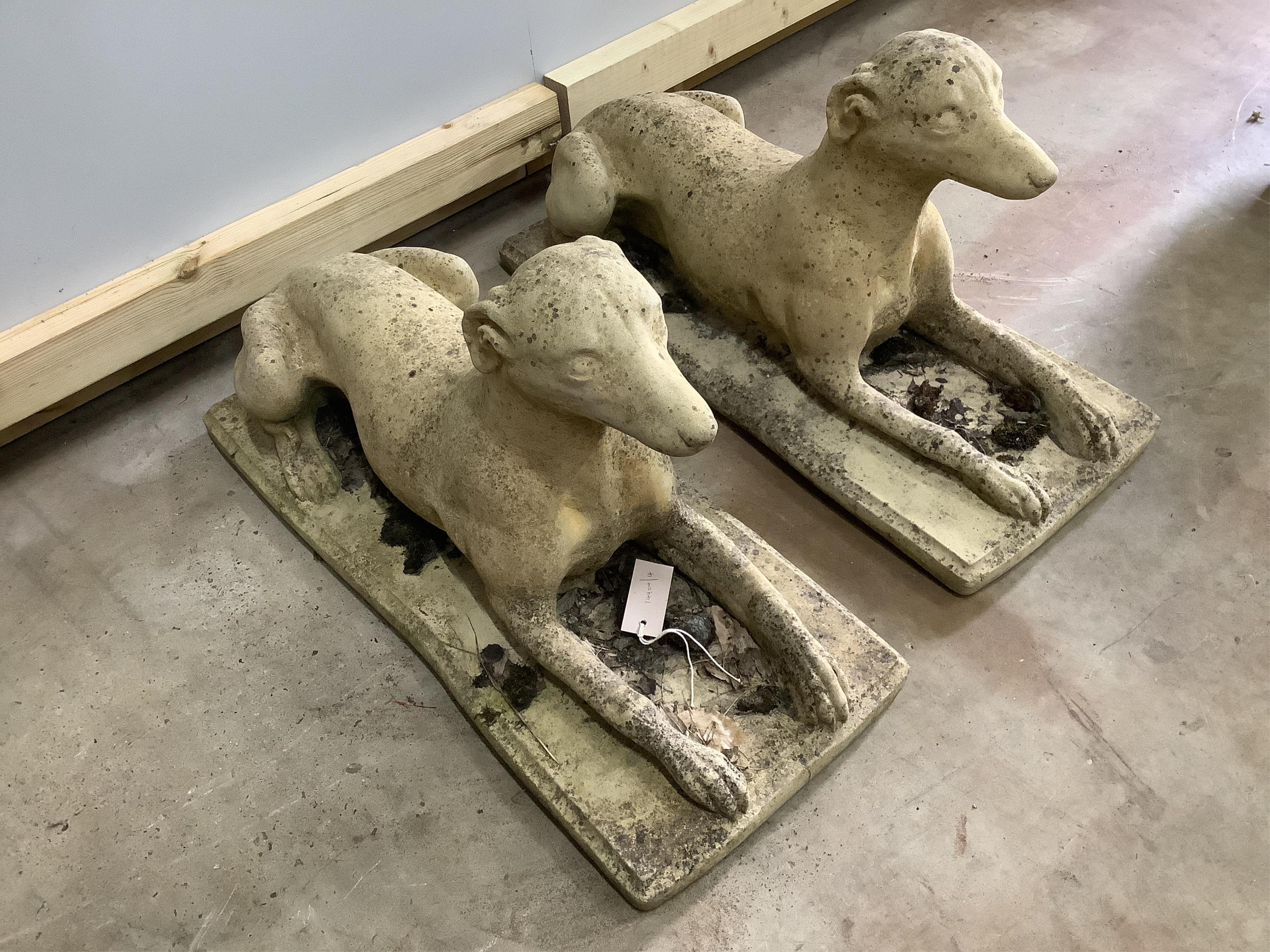 A pair of stone recumbent hound garden ornaments, length 70cm, width 30cm, height 34cm